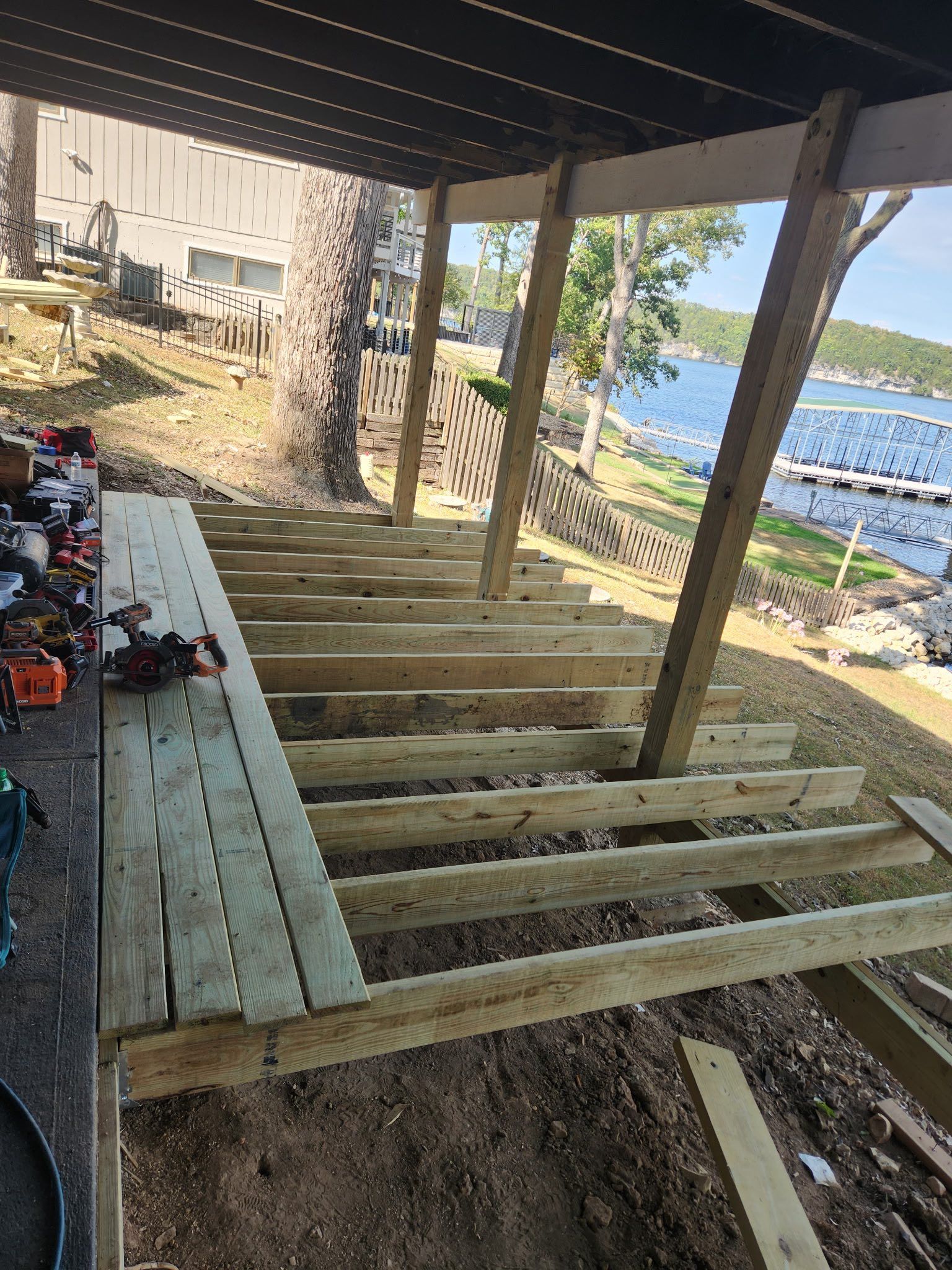 Wooden deck frame under construction with lake in background.
