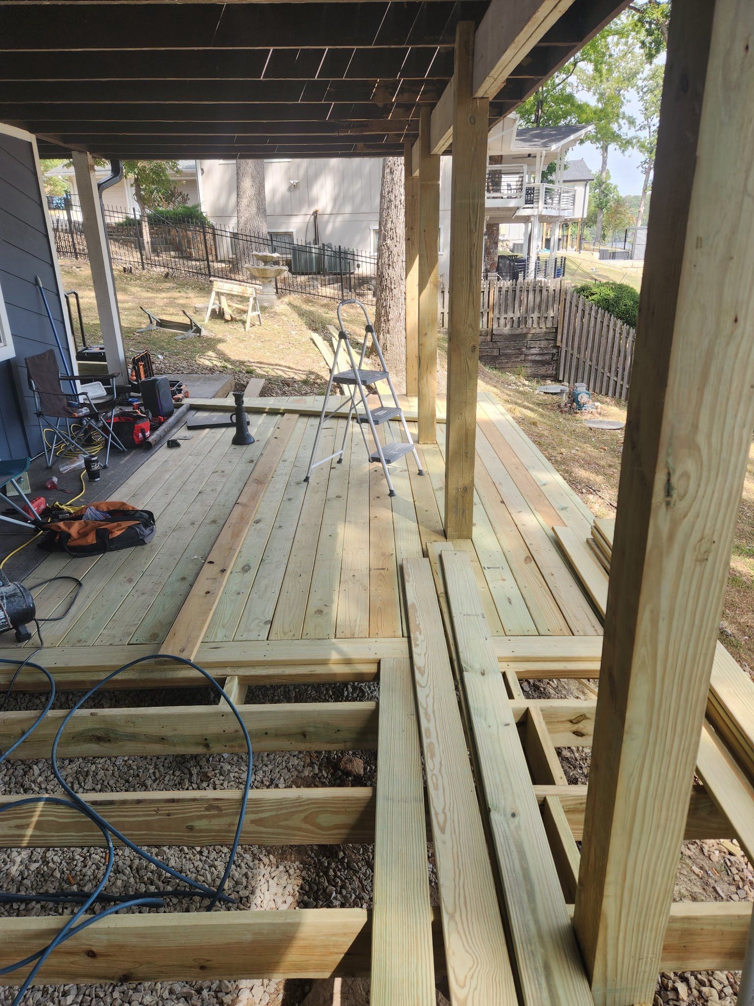 Deck construction in progress with wooden beams, flooring, and tools.