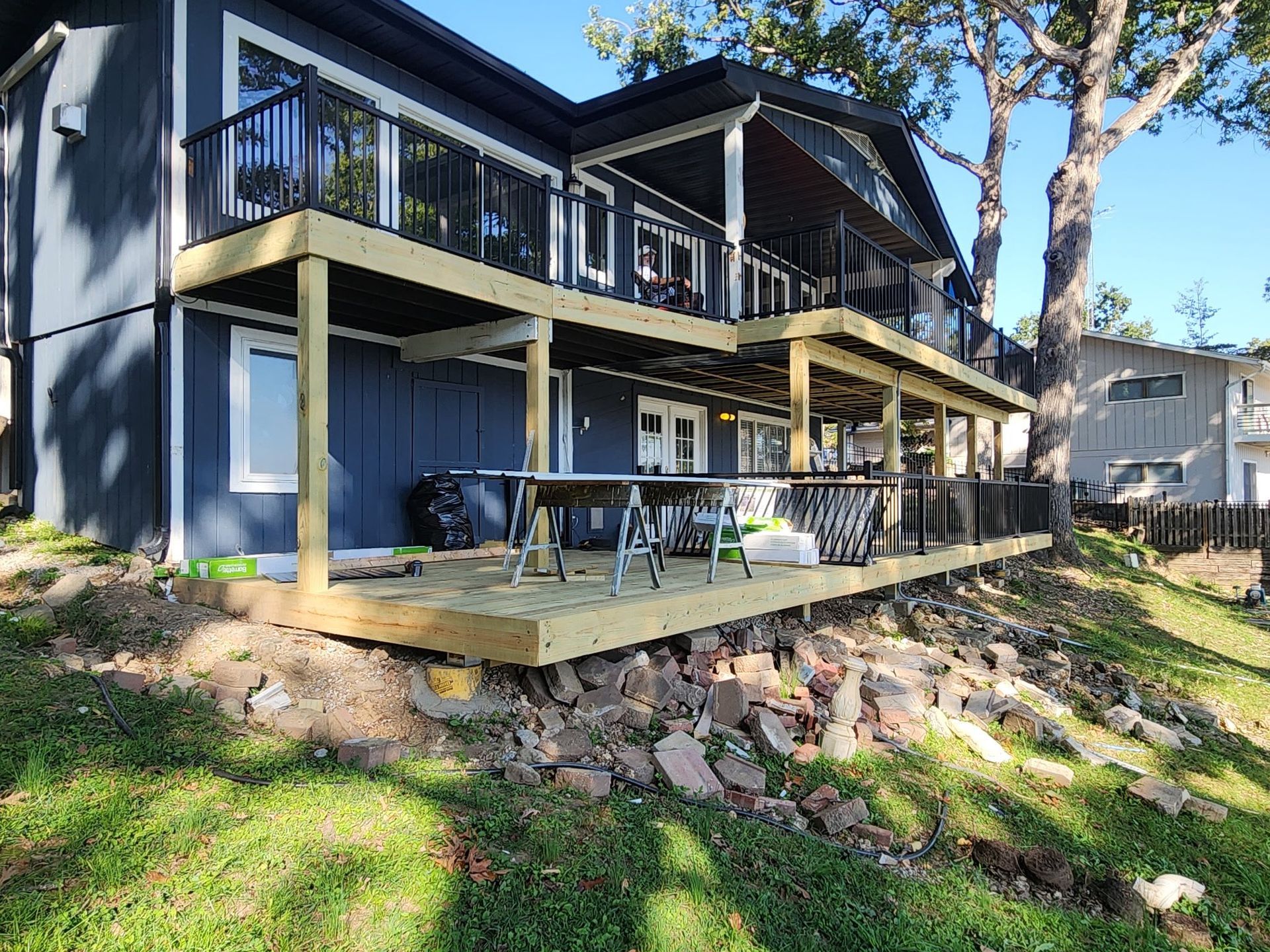 Two-story house with black trim and multiple wooden decks over a grassy slope.