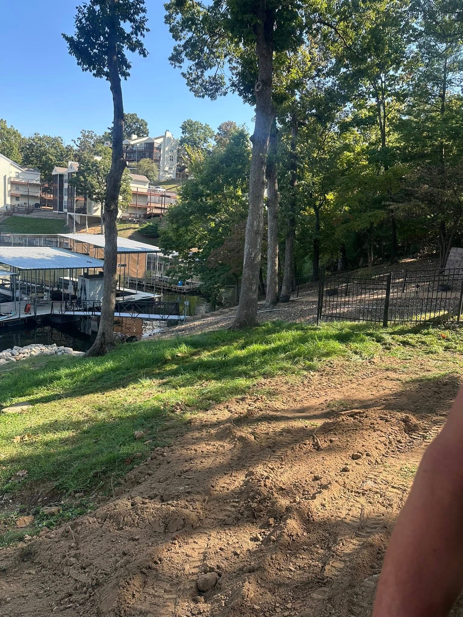 Lakeside scene with trees, docks, and buildings on a hillside under a clear sky.