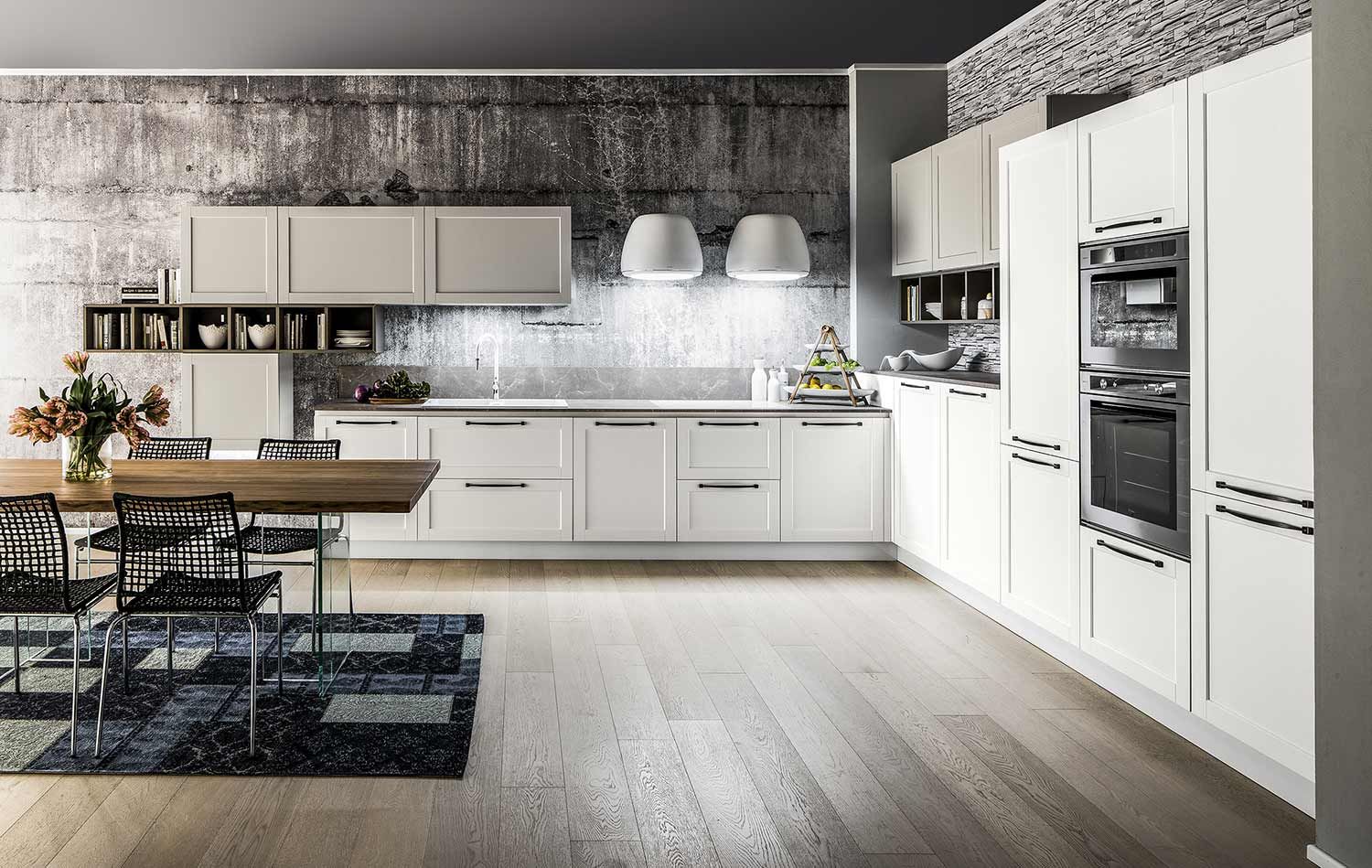 una cucina con mobili bianchi e tavolo e sedie in legno.