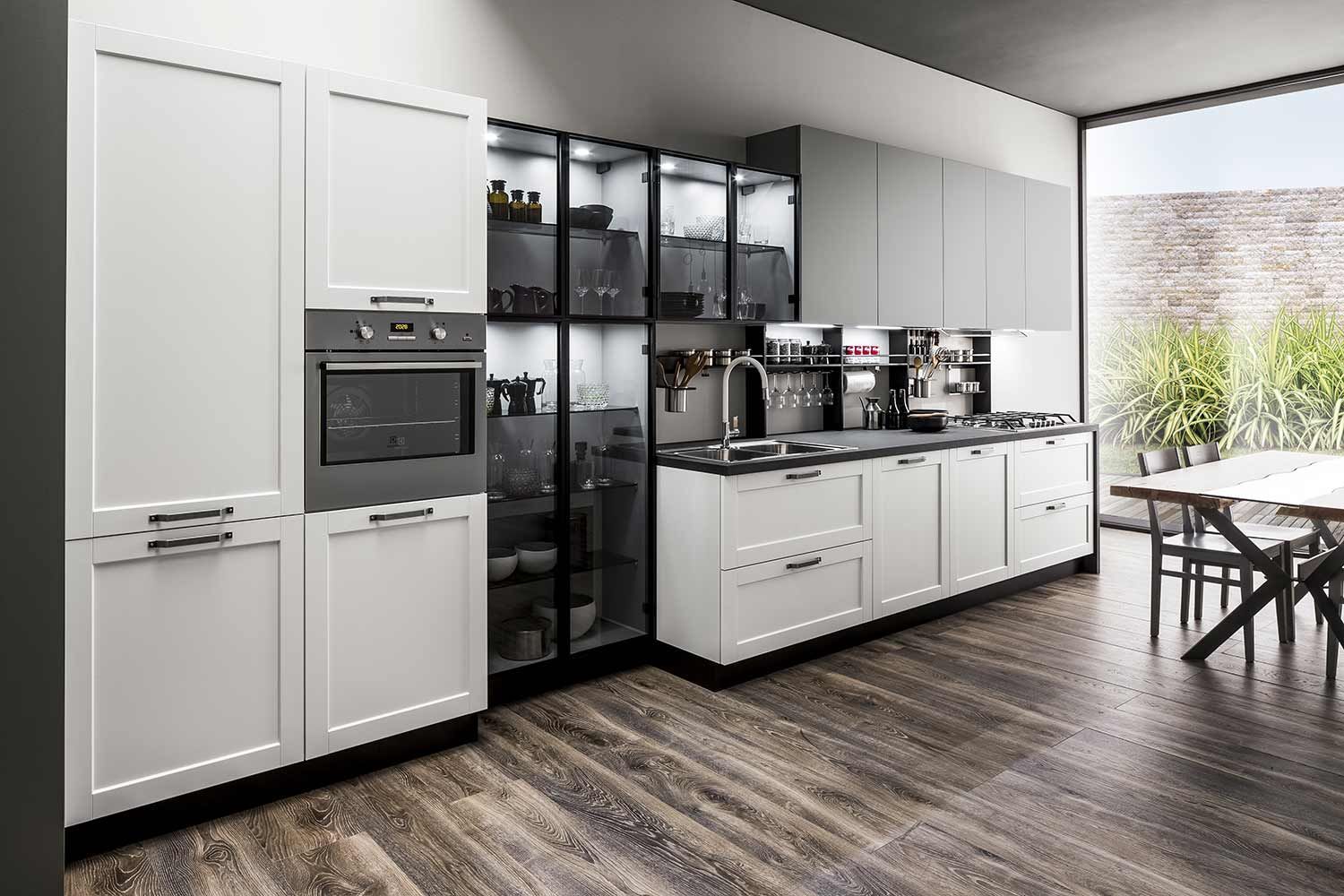 cucina con armadi bianchi e pavimenti in legno e una grande finestra.