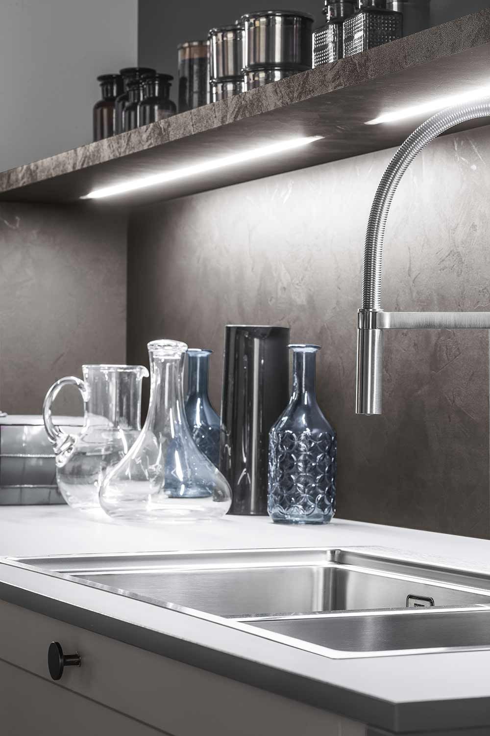 Lavello di una cucina con rubinetto e vasi sul ripiano.