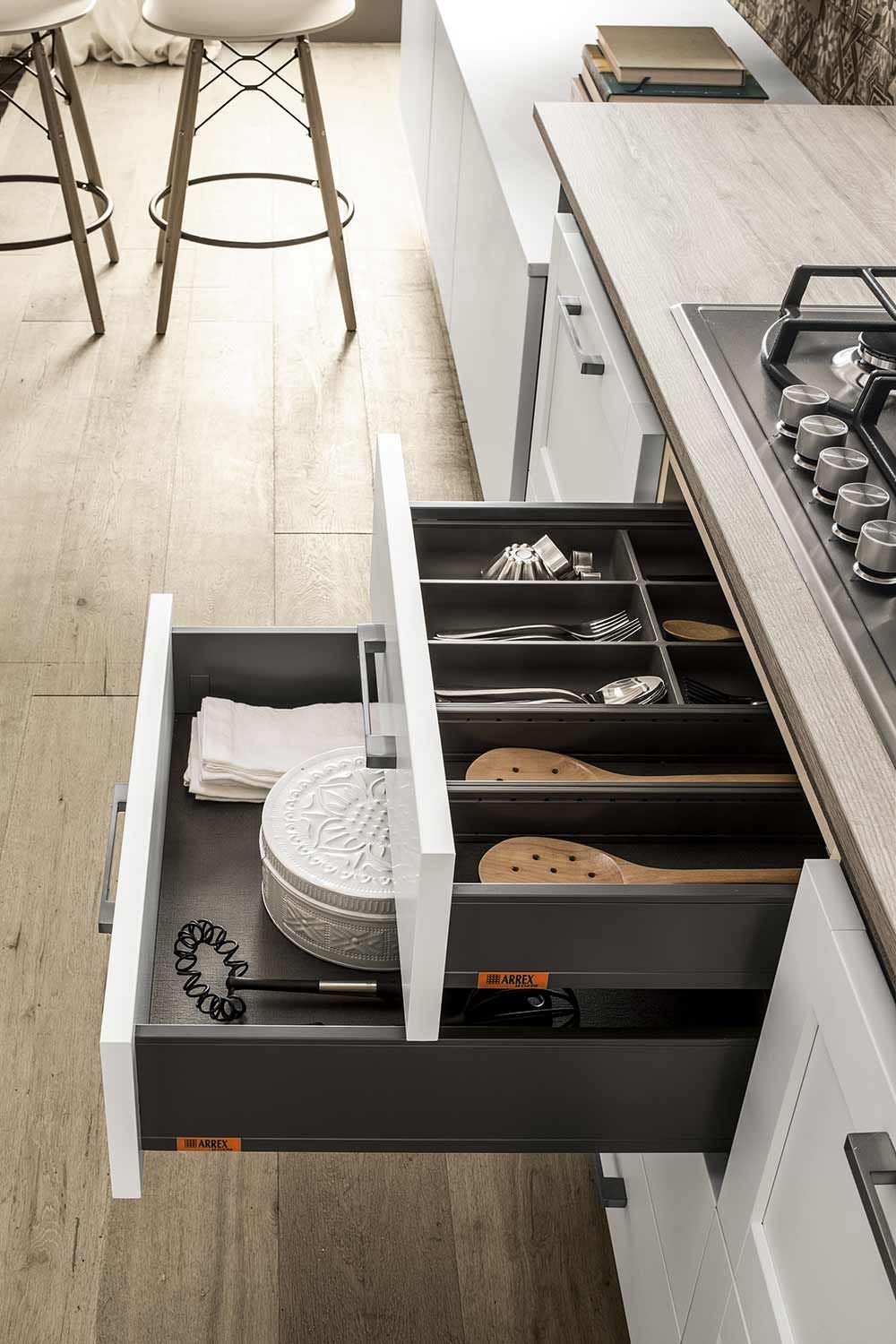 una cucina con forno e un cassetto pieno di utensili.