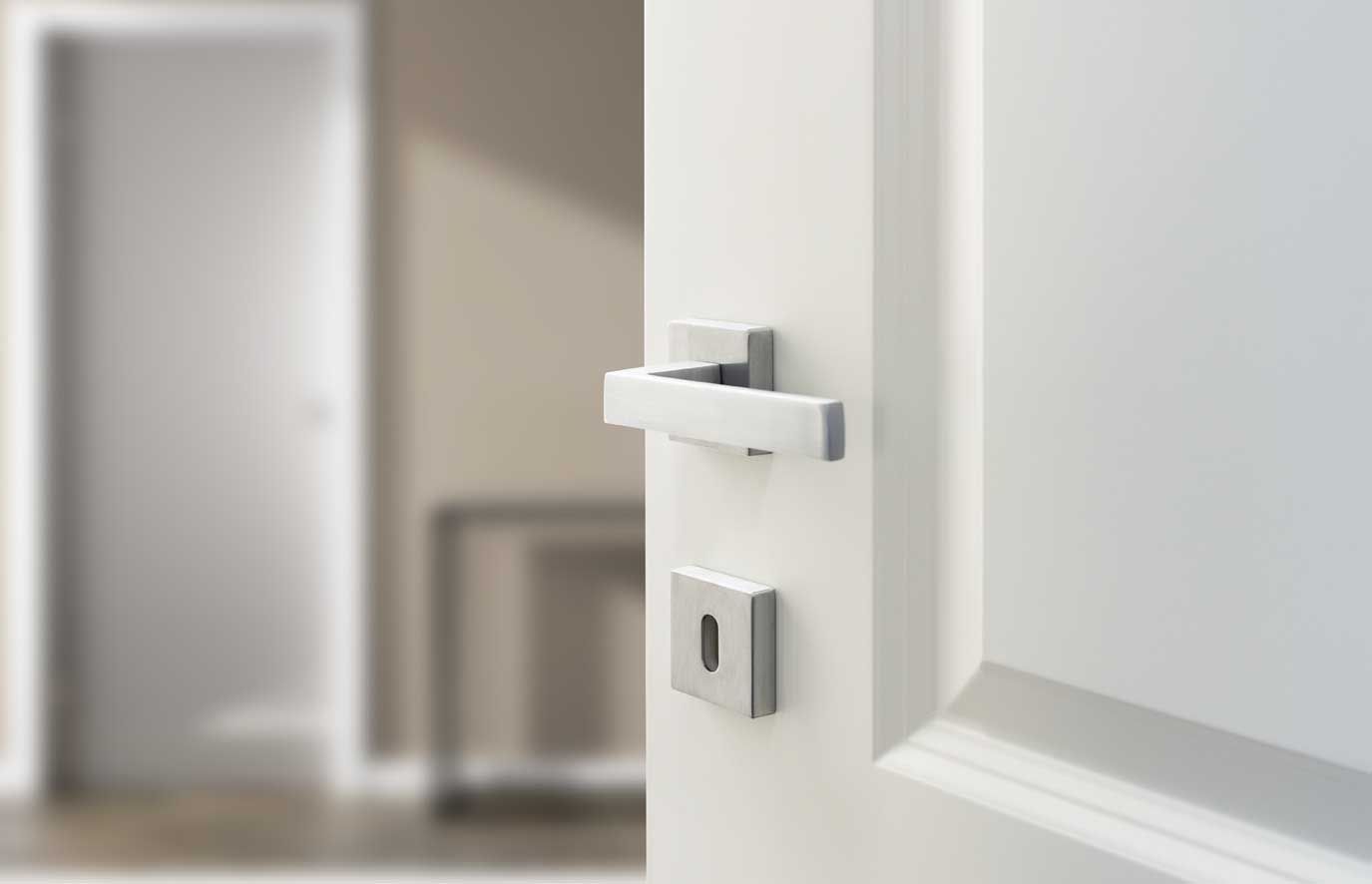 porta bianca con una maniglia d'argento aperta su una stanza