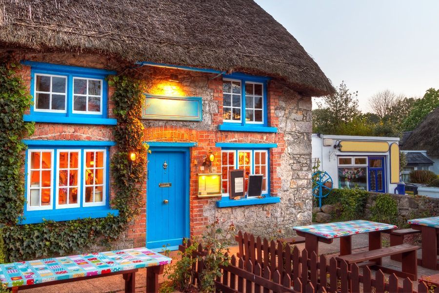 A thatched house with blue windows and a blue door