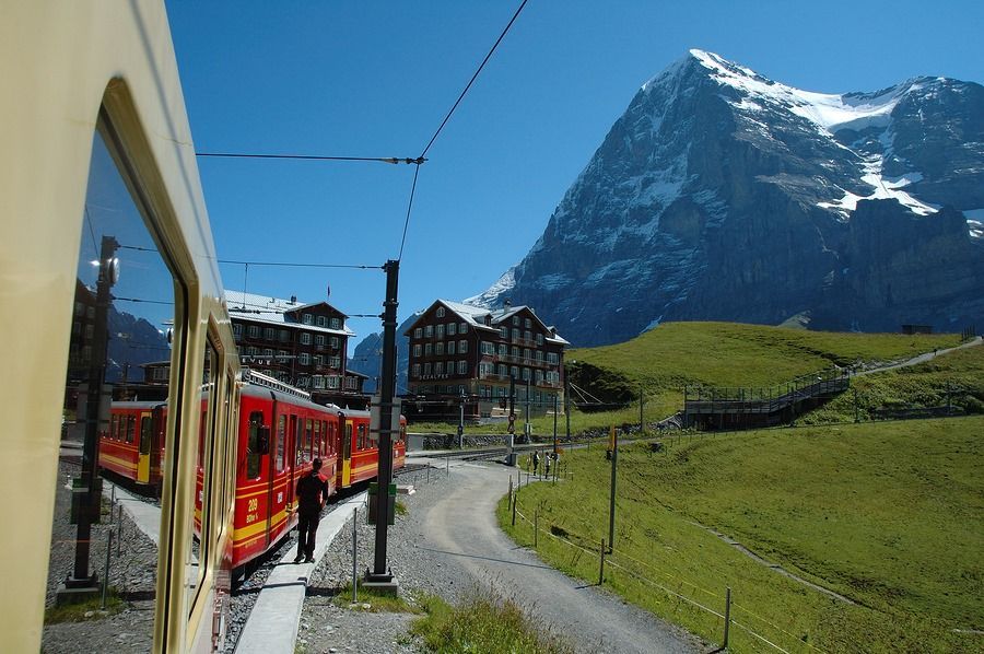 A train is pulling into a station with a mountain in the background