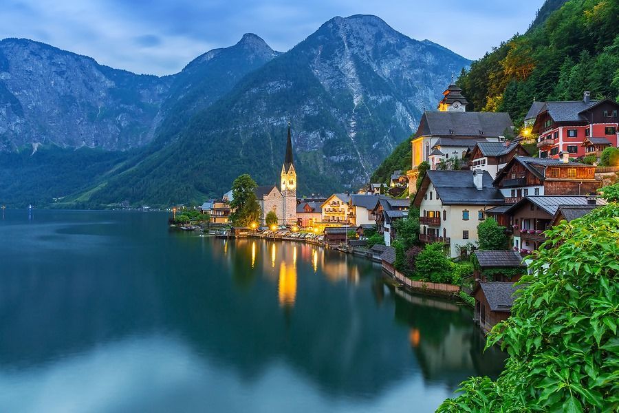 A small village on a lake with mountains in the background.