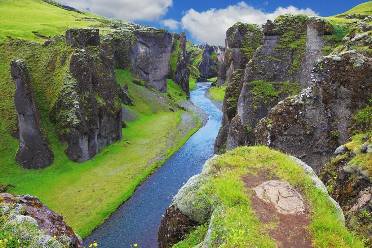 A river flowing through a canyon surrounded by rocks and grass.