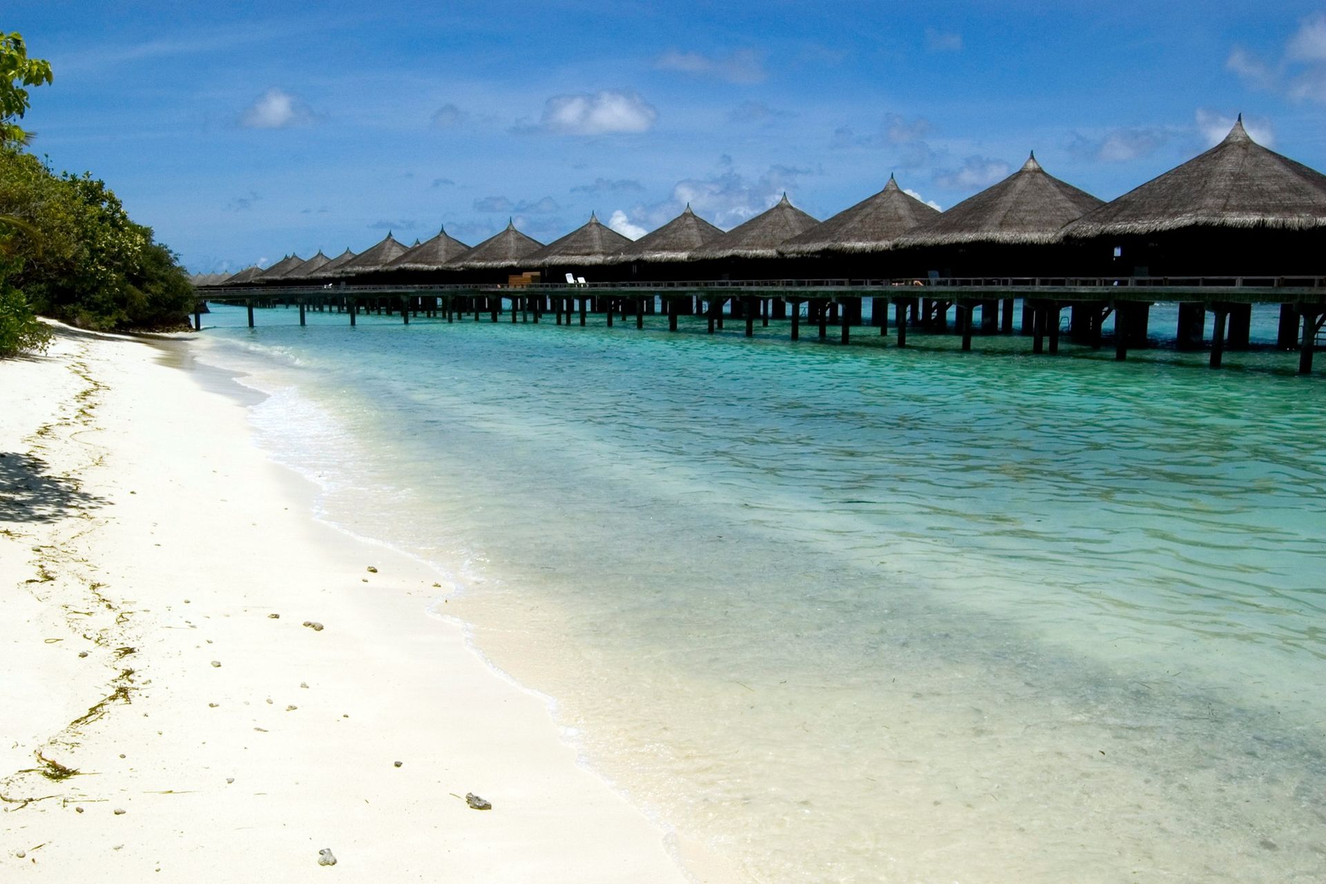 A beach with a row of bungalows in the water