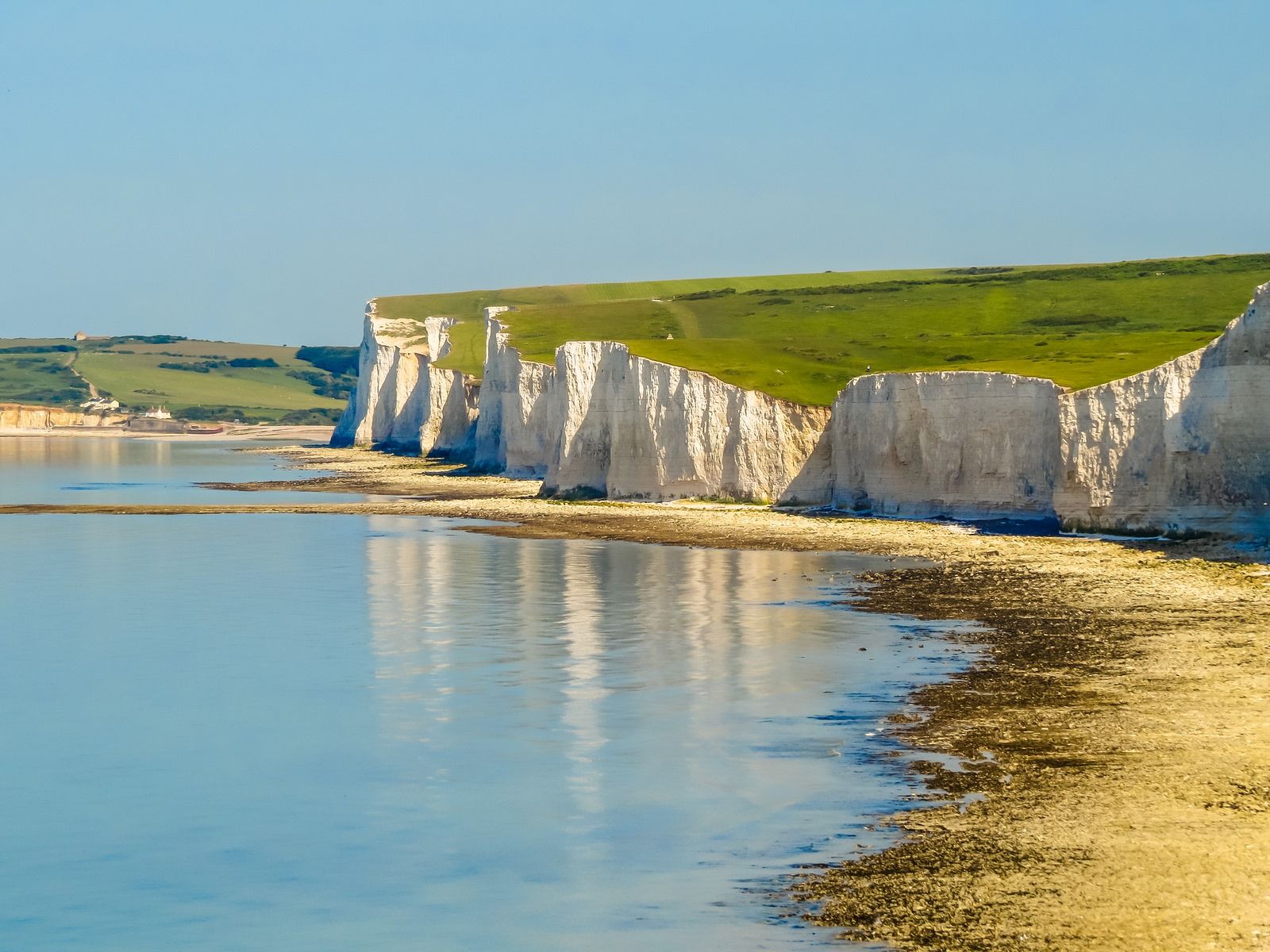 A beach with cliffs and a body of water in the background