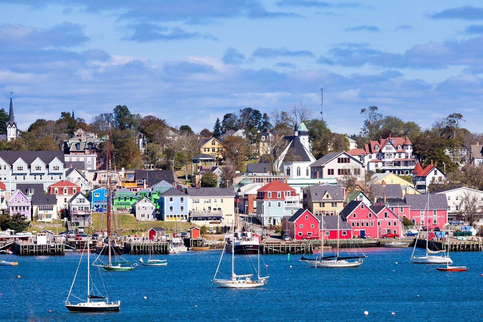 A group of sailboats are docked in front of a colorful town.