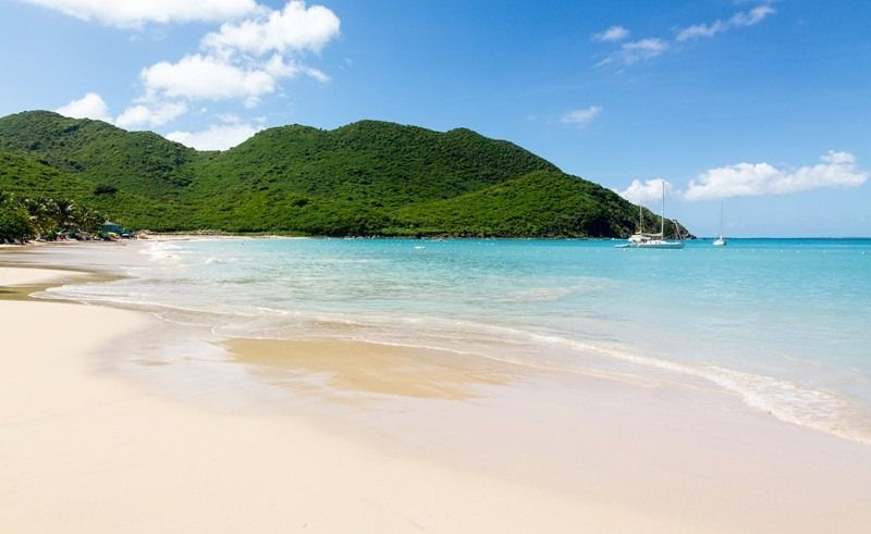 A beach with mountains in the background and a boat in the water.