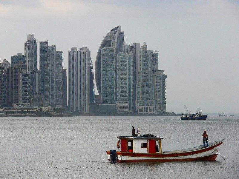 A boat in the water with a city skyline in the background