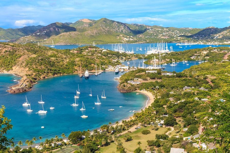 An aerial view of a tropical island with boats in the water and mountains in the background.