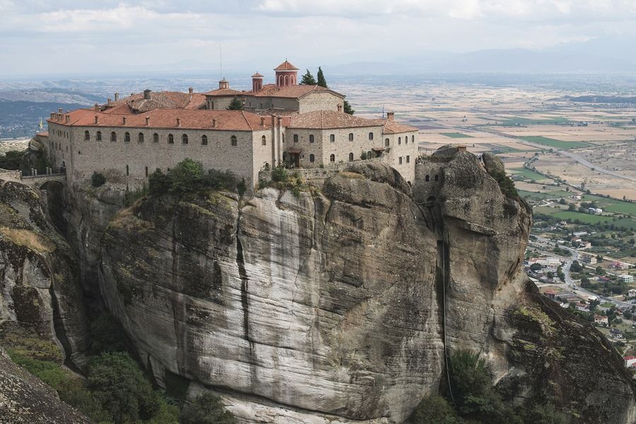 A large building is sitting on top of a rocky hill.