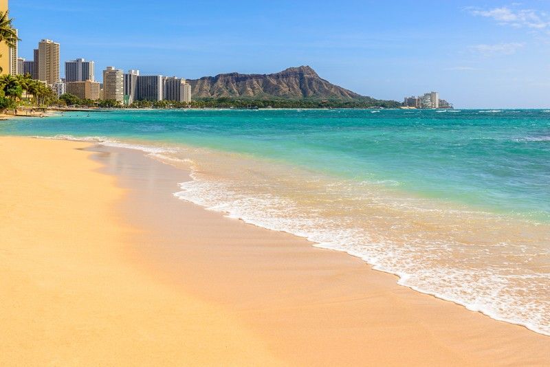 A beach with a mountain in the background and a city in the background.