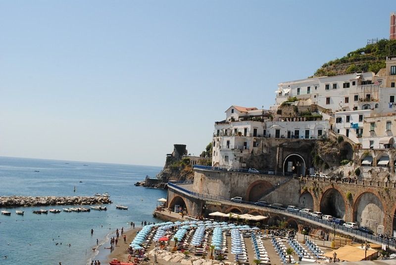 A beach with umbrellas and a city in the background
