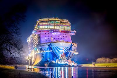 A large cruise ship is docked in the water at night.