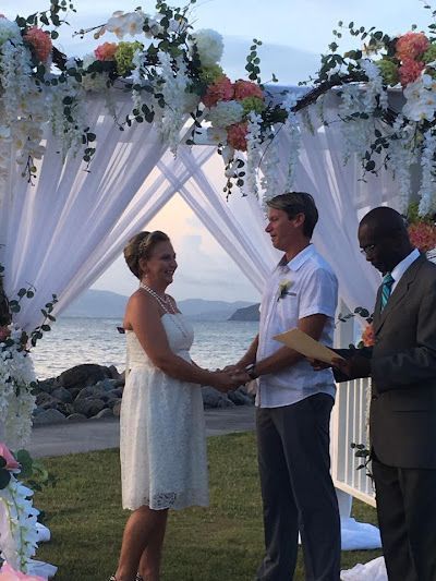 A bride and groom are holding hands during their wedding ceremony