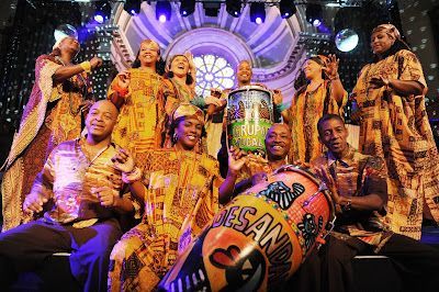 A group of people are posing for a picture on a stage with a drum that says ' jesus and mary ' on it