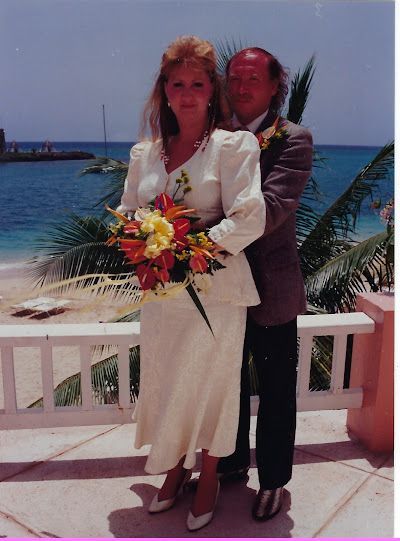 A bride and groom pose for a picture in front of the ocean