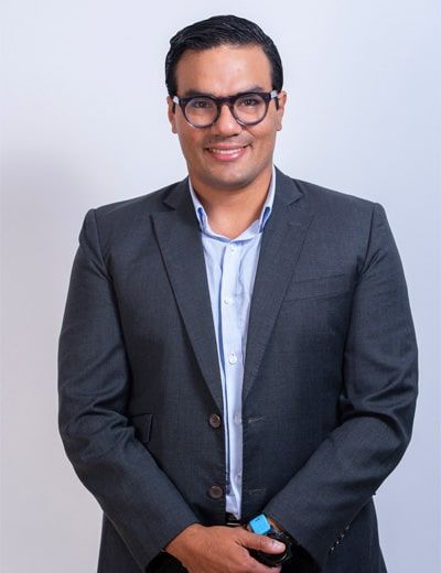 Un hombre con traje y gafas sonríe a la cámara.