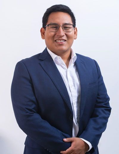Un hombre con traje azul y camisa blanca está sonriendo.