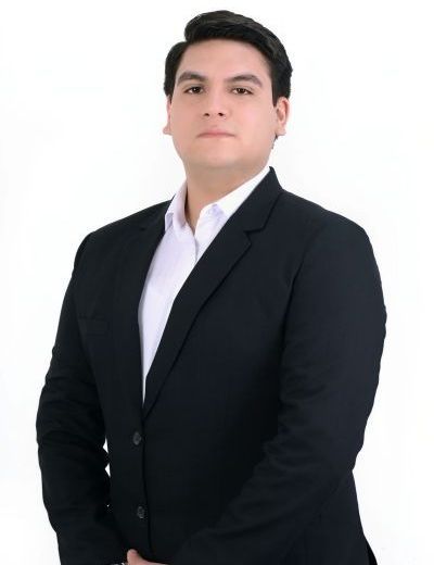 Un hombre con traje y camisa blanca está de pie frente a un fondo blanco.