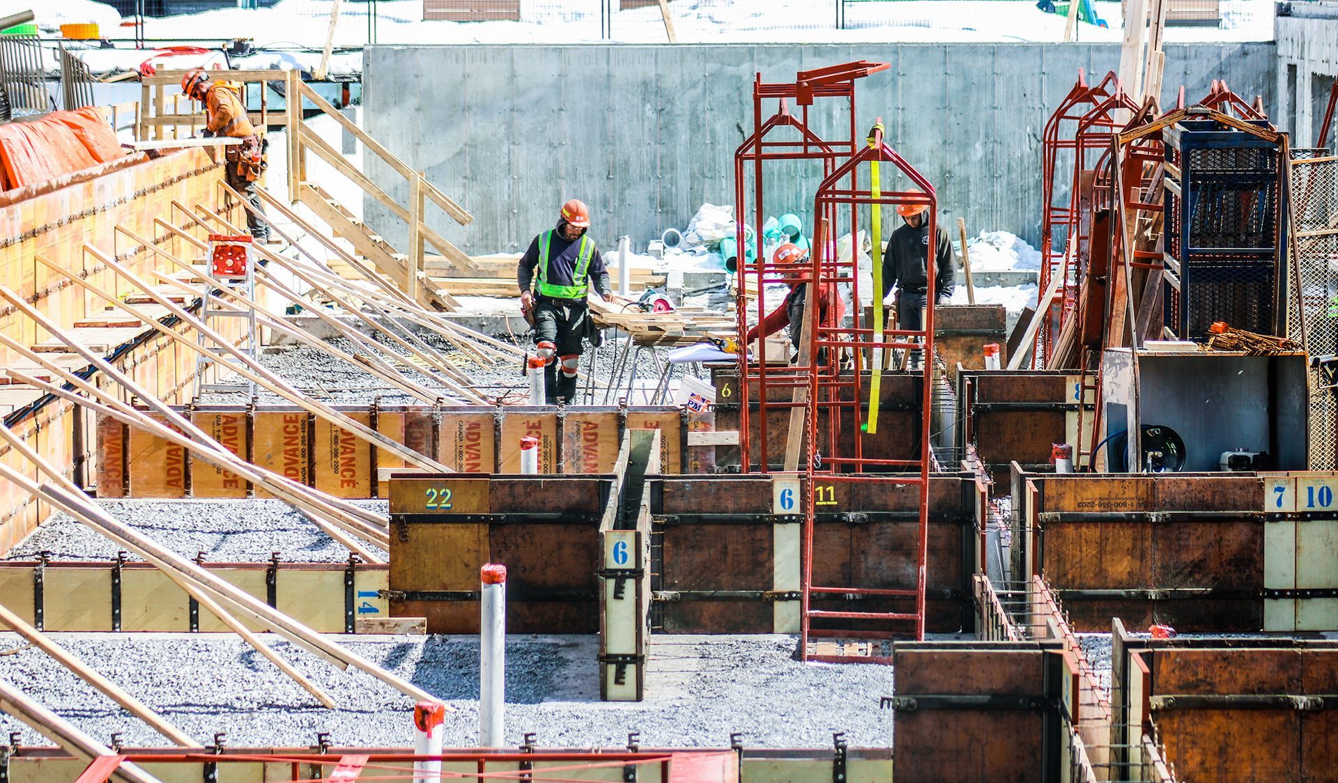 Chantier de construction avec ouvriers, échafaudages et coffrages en béton.