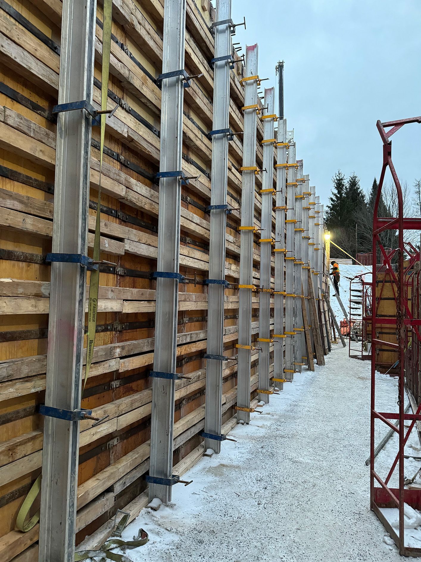 Coffrage en bois avec supports métalliques, chantier de construction, sol enneigé.