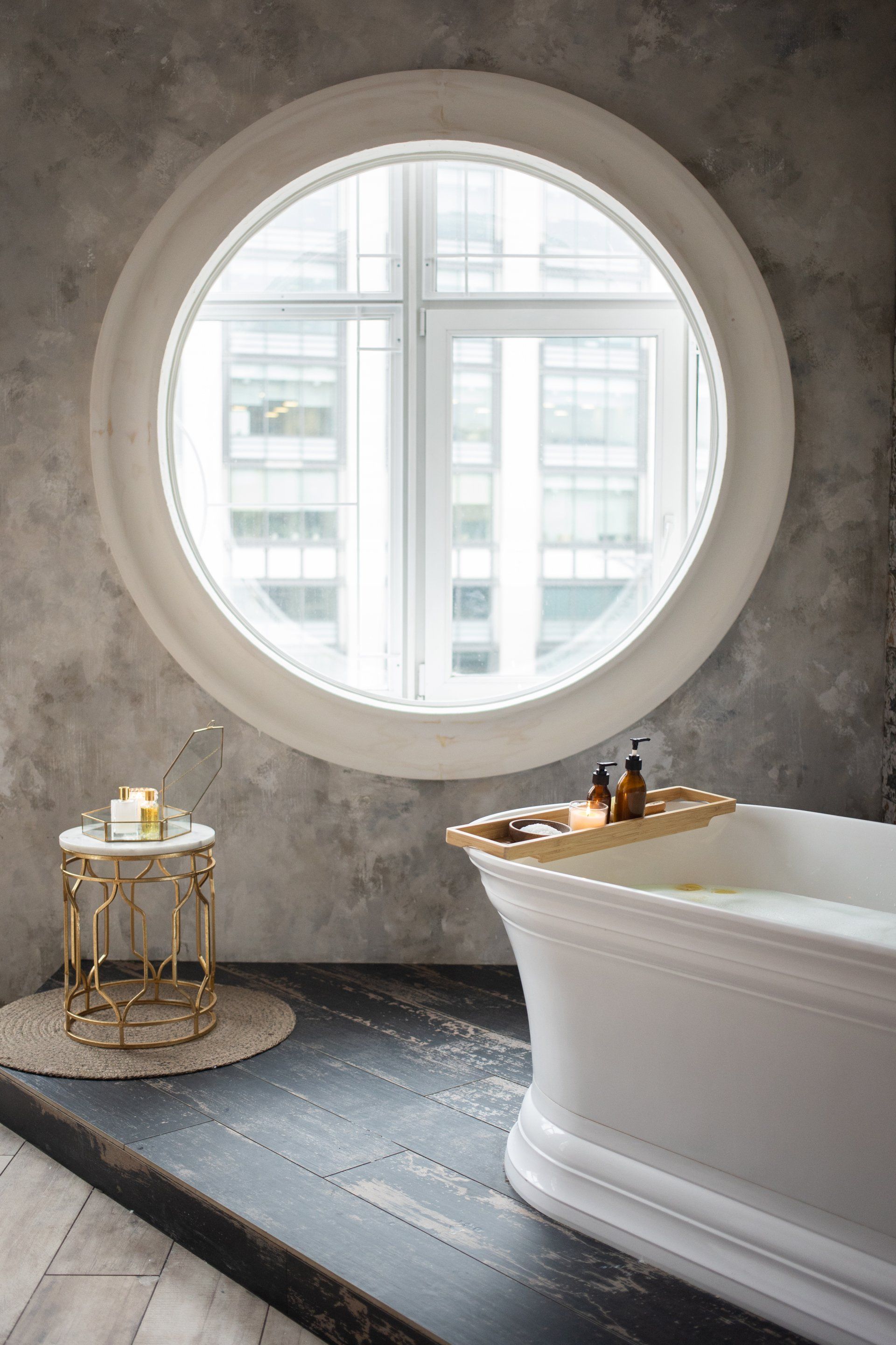 Free-standing bathtub next to circular window