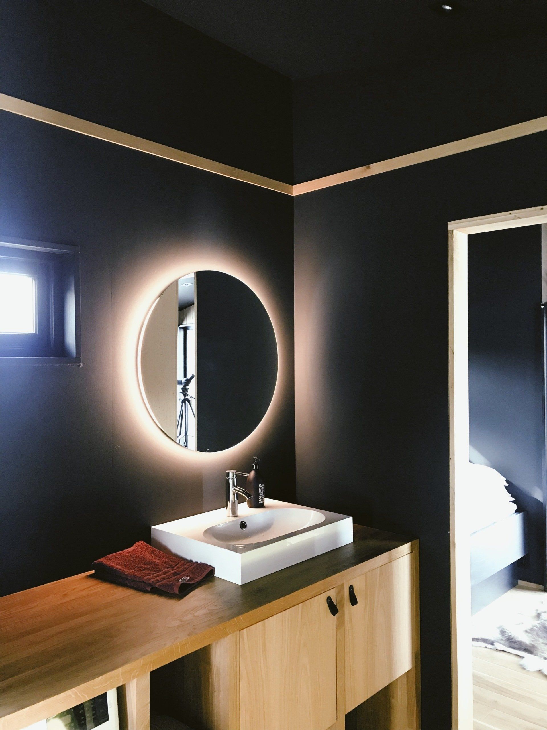 Dark bathroom with back-lit circle mirror