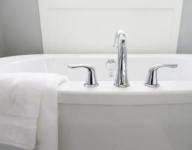 Silver faucet in bathtub and towel