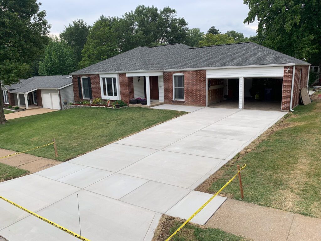 A brick house with a concrete driveway in front of it