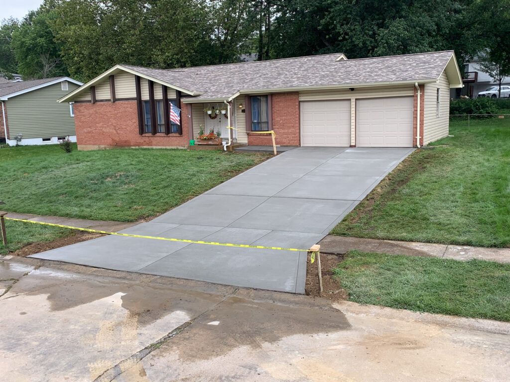 A brick house with a concrete driveway in front of it.