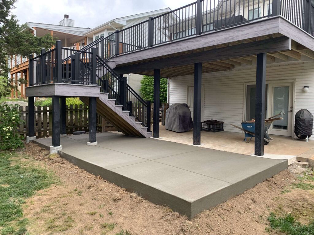 A large deck with stairs leading up to it is being built in the backyard of a house.