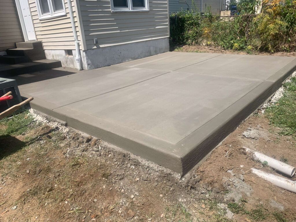 A concrete patio is being built in front of a house.