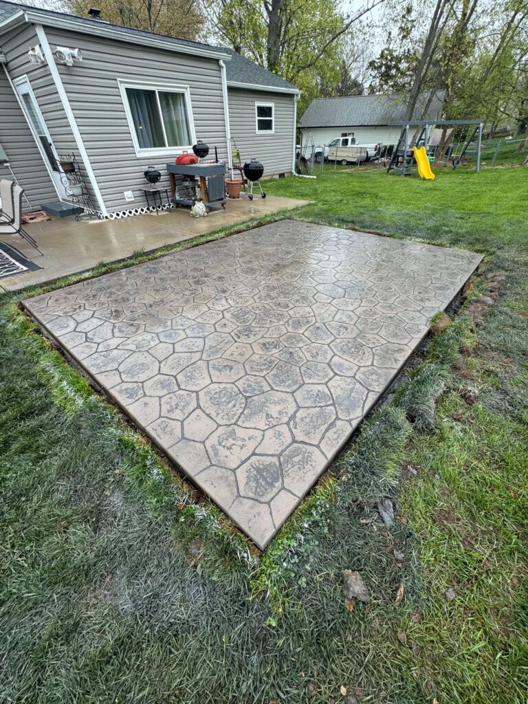 A concrete patio in a backyard next to a house.