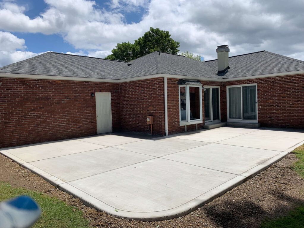 A brick house with a concrete patio in front of it.