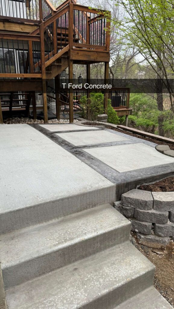 A concrete patio with stairs and a wooden deck.