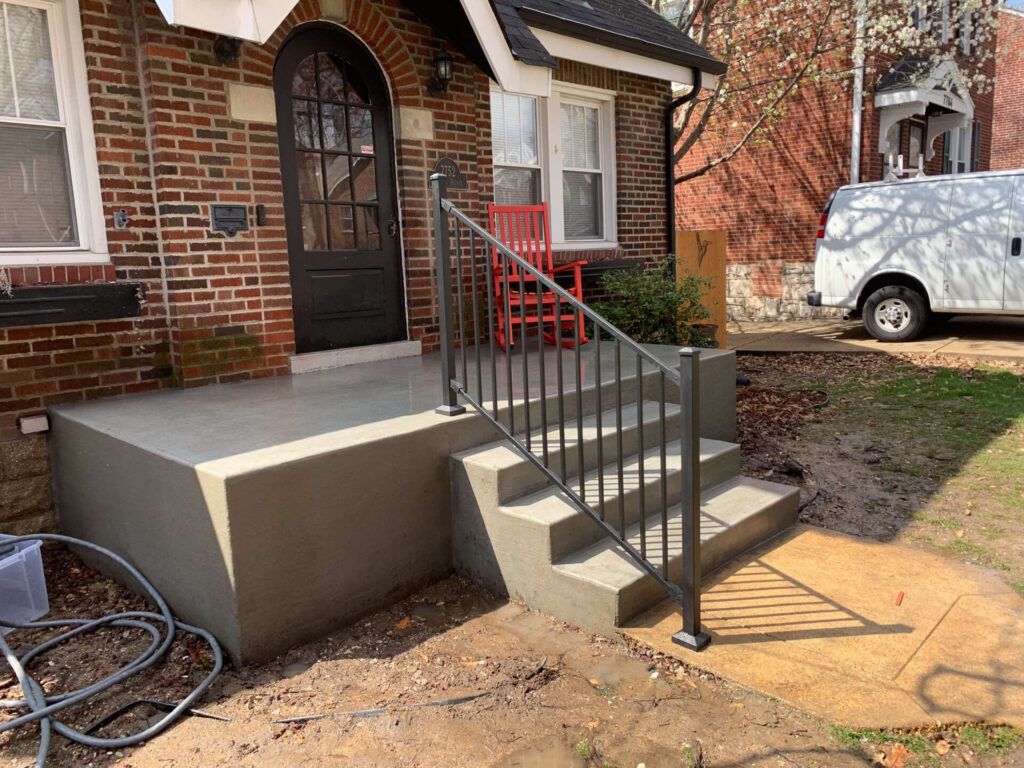 A white van is parked in front of a brick house with stairs and a railing.
