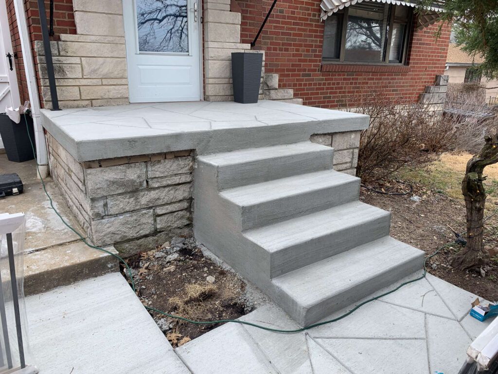 A set of concrete steps leading up to a porch of a house.
