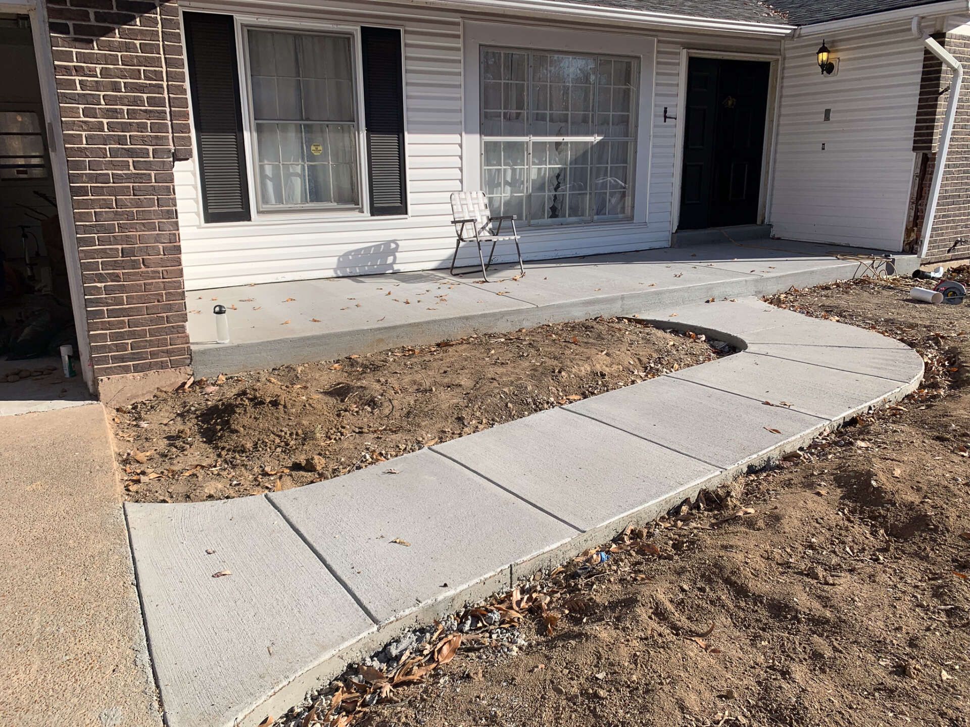 A concrete walkway is leading to the front of a house.