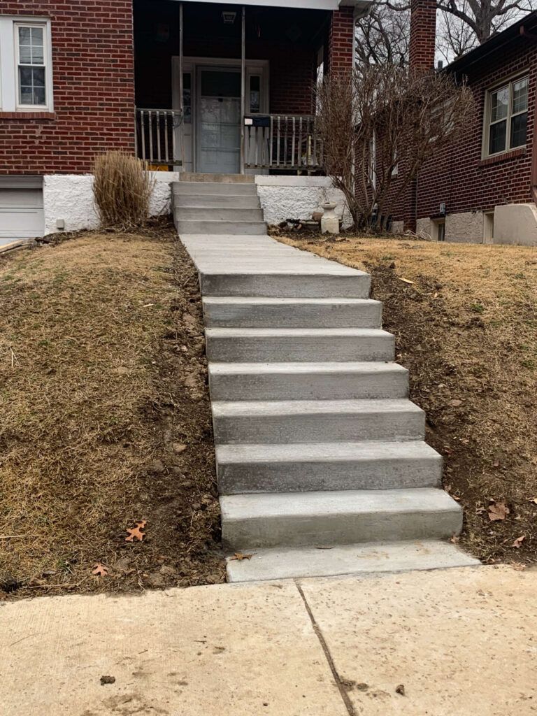 A set of concrete stairs leading up to a brick house.