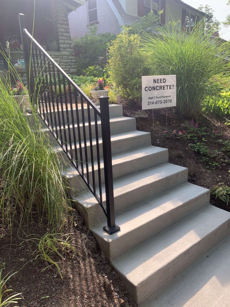 A set of concrete stairs with a metal railing and a sign on the side.