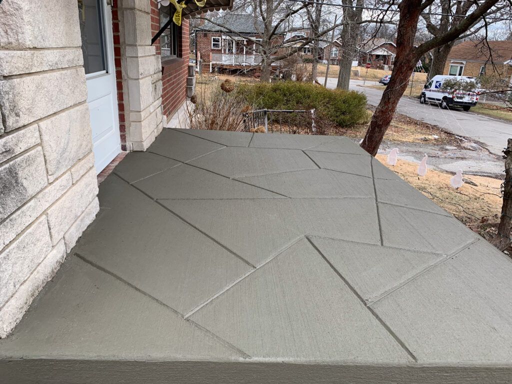 A concrete porch next to a brick building with a car parked in front of it.