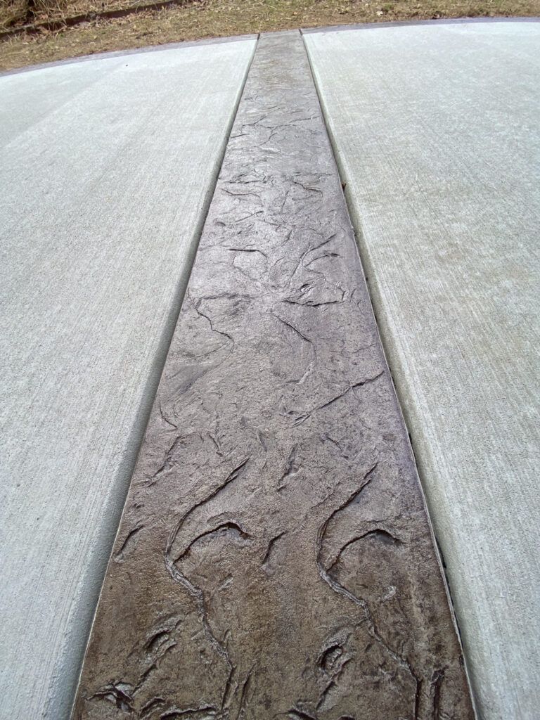 A close up of a concrete driveway with a pattern on it.