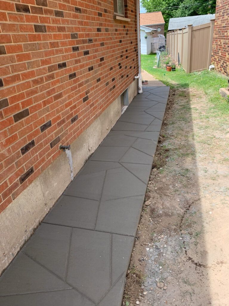 A sidewalk is being built in front of a brick house.