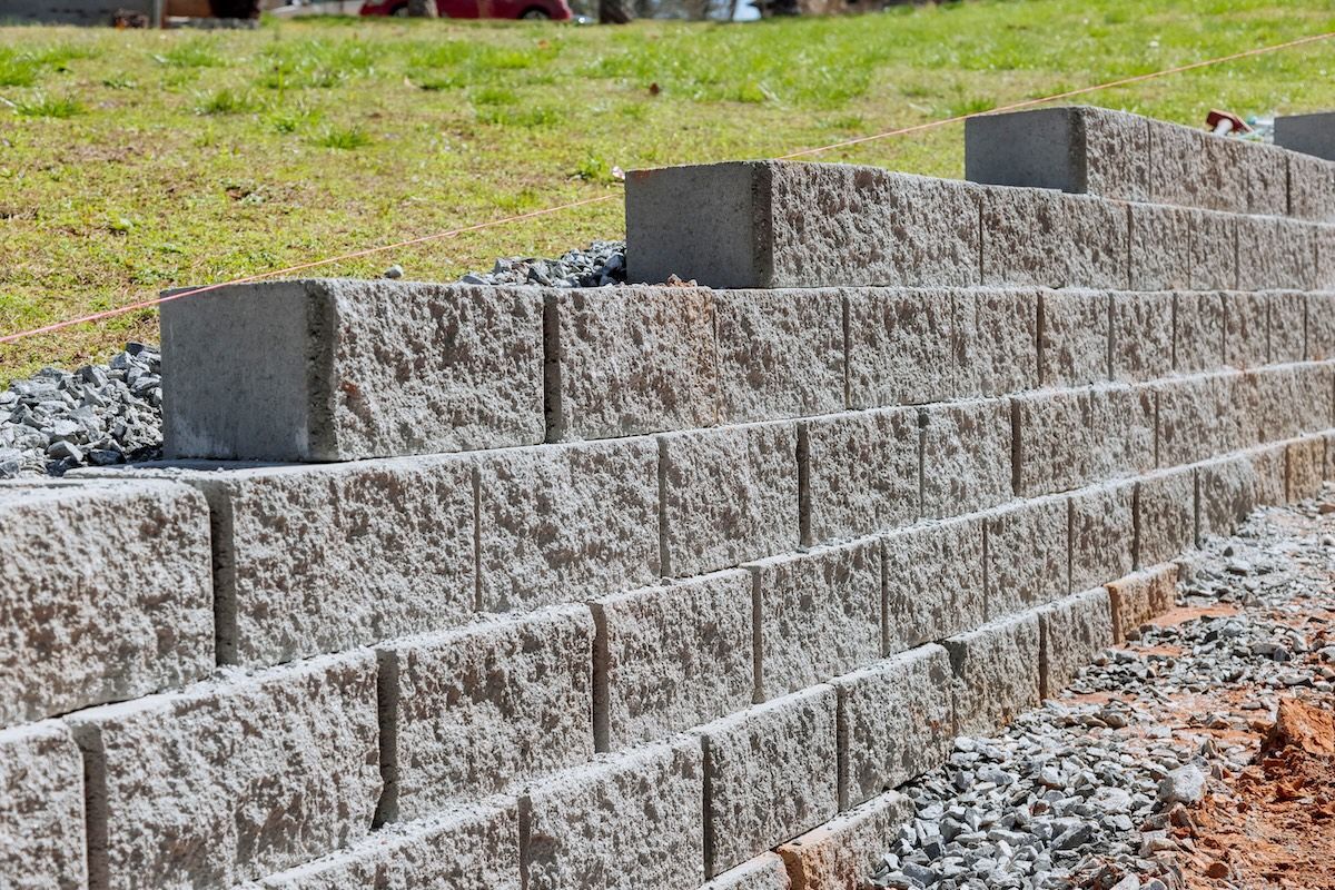 A brick wall is being built on top of a grassy hill.